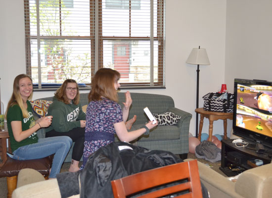 residents in the village townhouse have fun playing a video game on their widescreen tv in their furnished living room