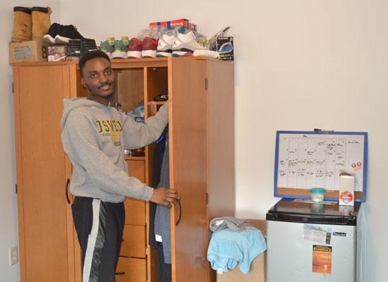 student taking a shirt out of this wardrobe in his village townhouse bedroom