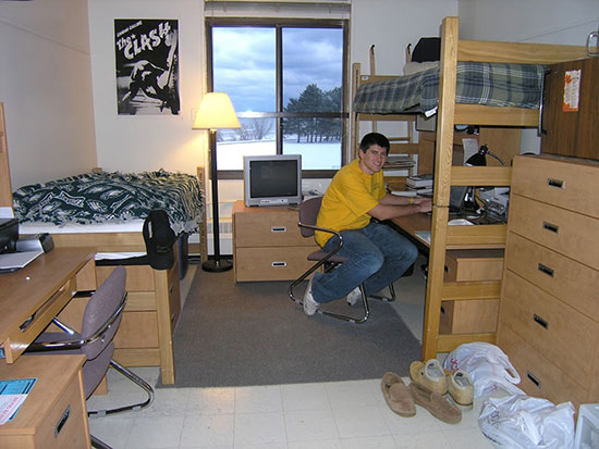 This male student's room features the lofted bed with a work surface underneath option and a default style bed option.