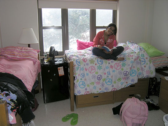 Female student reading on her bed in a Hart Hall bedroom.