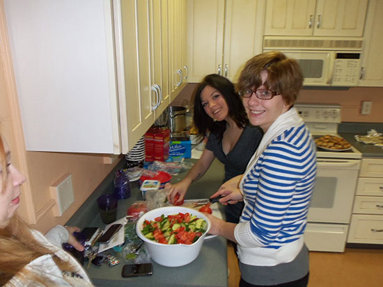 Female students prepare a salad in the Mackin Complex kitchen.