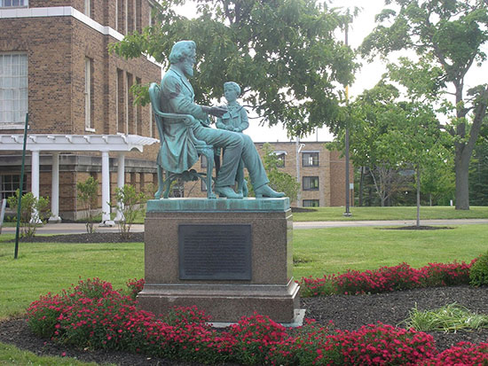 Statue of Edward Austin Sheldon, SUNY Oswego's founder, in front of Sheldon Hall with Moreland Hall in the background.