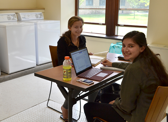 Residents study while doing their laundry in the clean and spacious Riggs Hall laundry room.