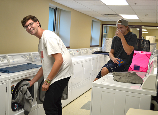 Seneca Hall residents in the bright, clean, large, and spacious laundry room.