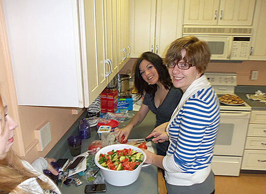 Mackin Complex main kitchen. 2 female students making a green salad.