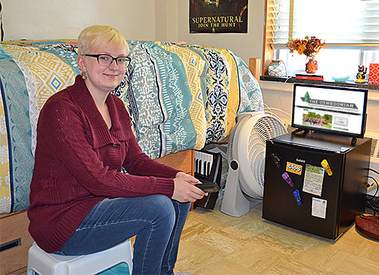 Student sits in her Funnelle Hall room watching tv.