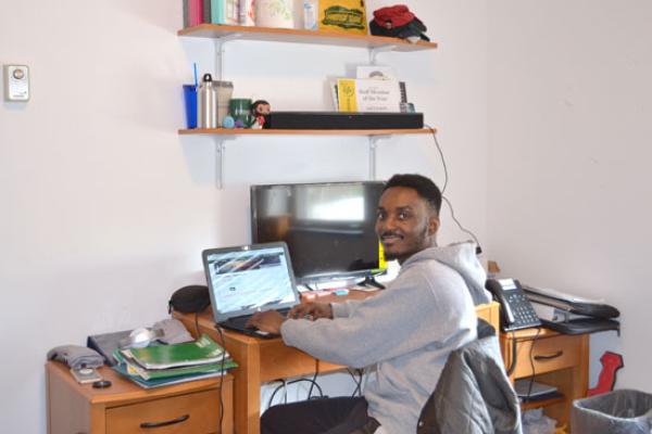 male student working at his desk in his village townhouse bedroom.