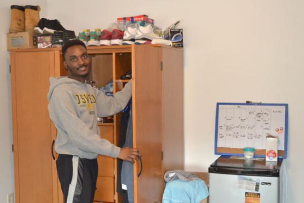 student taking a shirt out of this wardrobe in his village townhouse bedroom