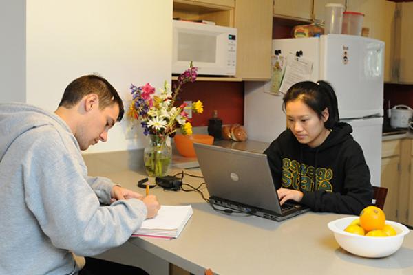 Two students doing homework sitting at the peninsula in the kitchen at The Village.
