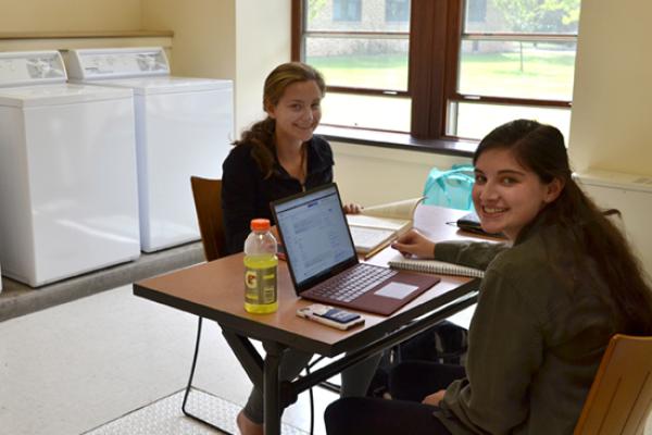 Residents study while doing their laundry in the clean and spacious Riggs Hall laundry room.