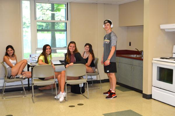 A group of residents study at a table in the kitchen area while doing their laundry next door in the Seneca Hall laundry room.