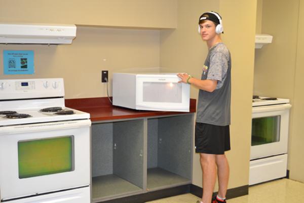 A Seneca Hall resident warms up a snack in the microwave located in the large kitchen area.