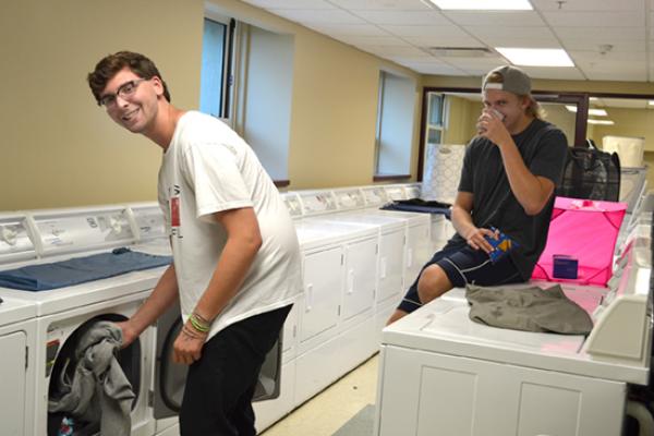 Seneca Hall residents in the bright, clean, large, and spacious laundry room.