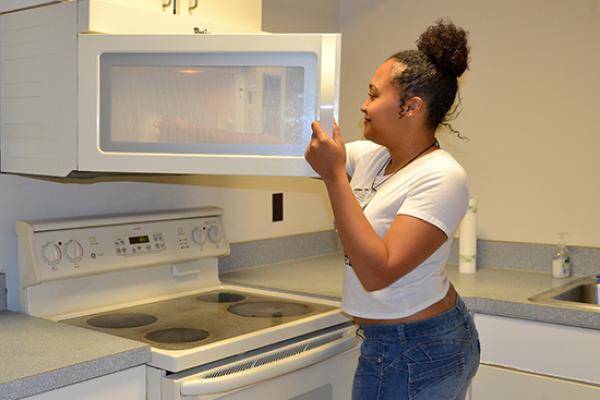 Hart Hall resident reaches for her tea in the microwave in the 3rd floor kitchenette.