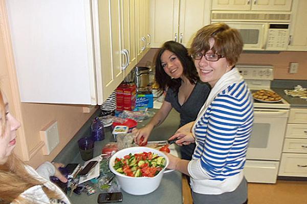 Mackin Complex main kitchen. 2 female students making a green salad.