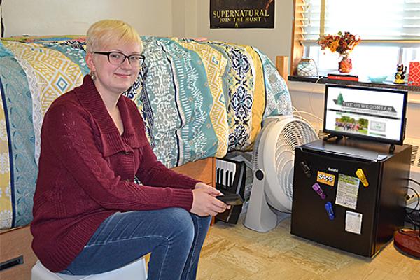 Student sits in her Funnelle Hall room watching tv.