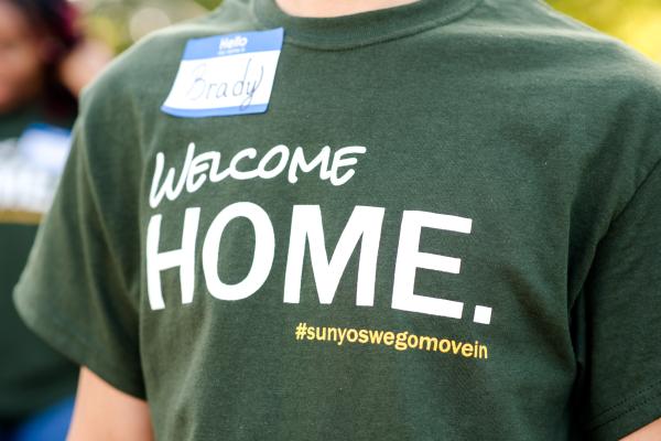 A close-up shot of a Laker Move-In Crew member's t-shirt. The T-shirt reads "Welcome Home." #sunyoswegomovein