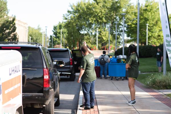 Two Laker Move-In Crew members standing on the sidewalk and directing traffic