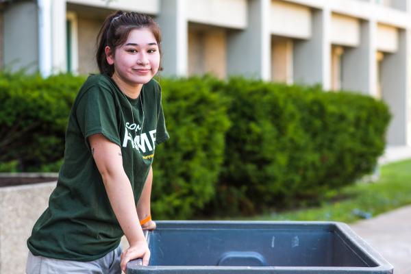 A Laker Move-In Crew member standing to the left of a gray moving bin