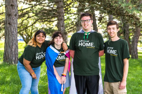 Four Laker Move-In Crew members standing in a shady area, facing the camera and smiling