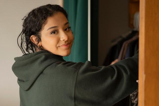 A student facing the camera, reaching to take an item out of their dresser in their Funnelle Hall room