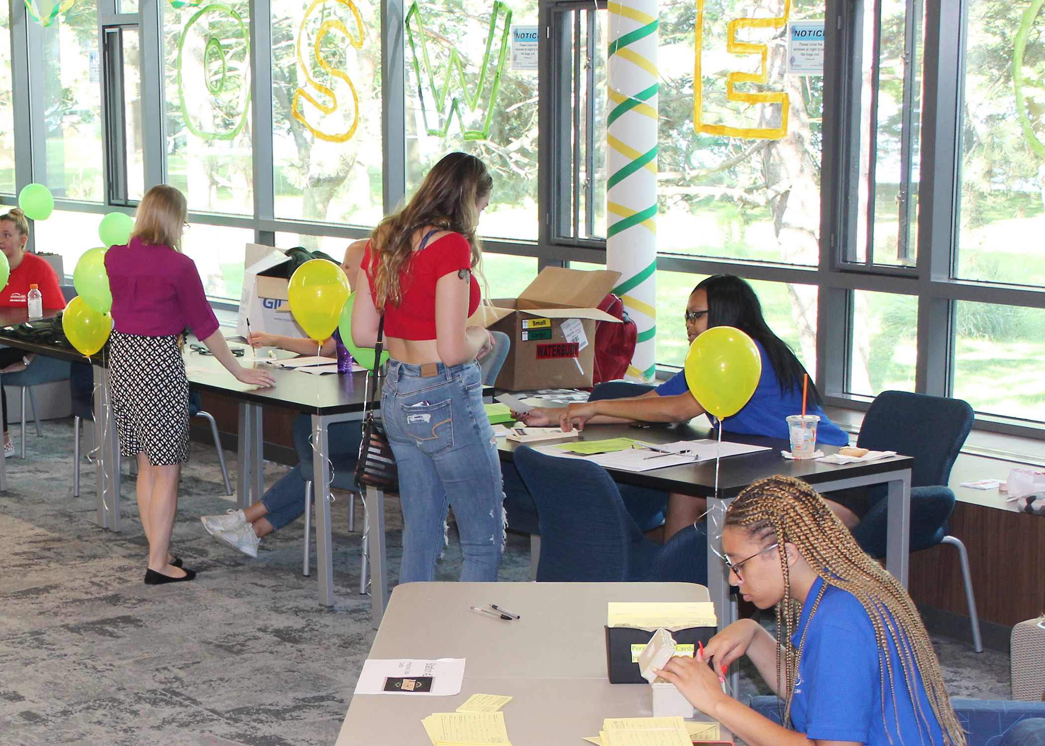 Image of several Resident Assistants sitting at tables and checking incoming students in