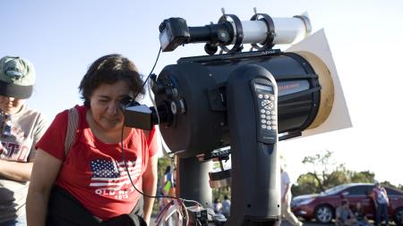 Woman looks through a telescope during the day