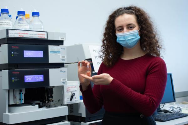 Miryam holding a vial by the LC machine Miryam holding a vial by the LC machine