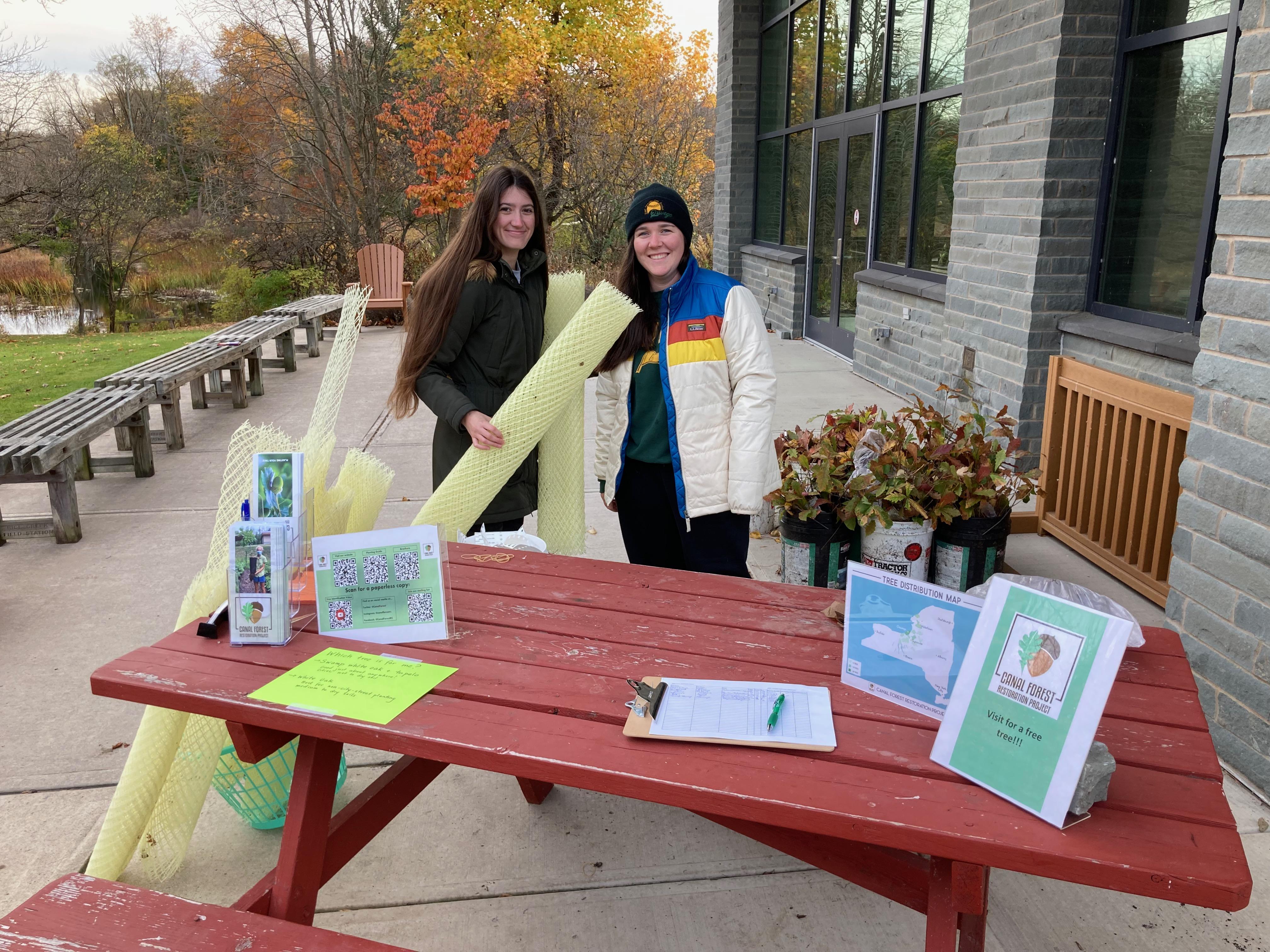 two women at a table, giving away trees