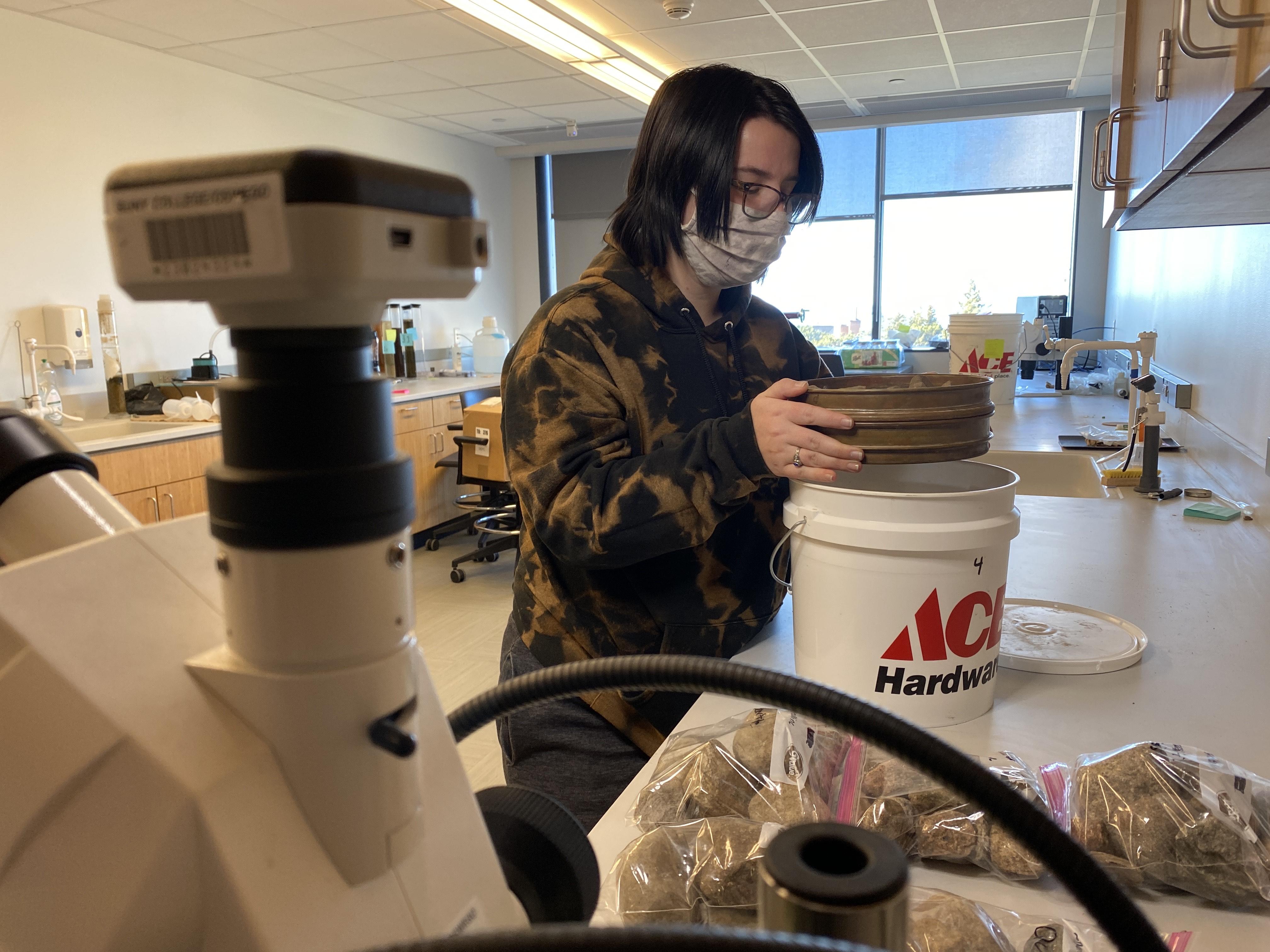 Kathryn in the laboratory with a sieve and sediments