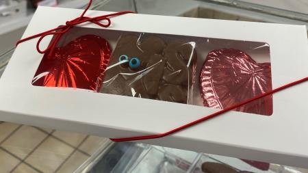 Box of hand-made candies - pink and red foil wrapped hearts and chocolate "Kiss"