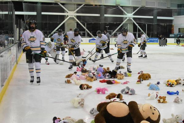 hockey players sweeping up teddy bears on ice
