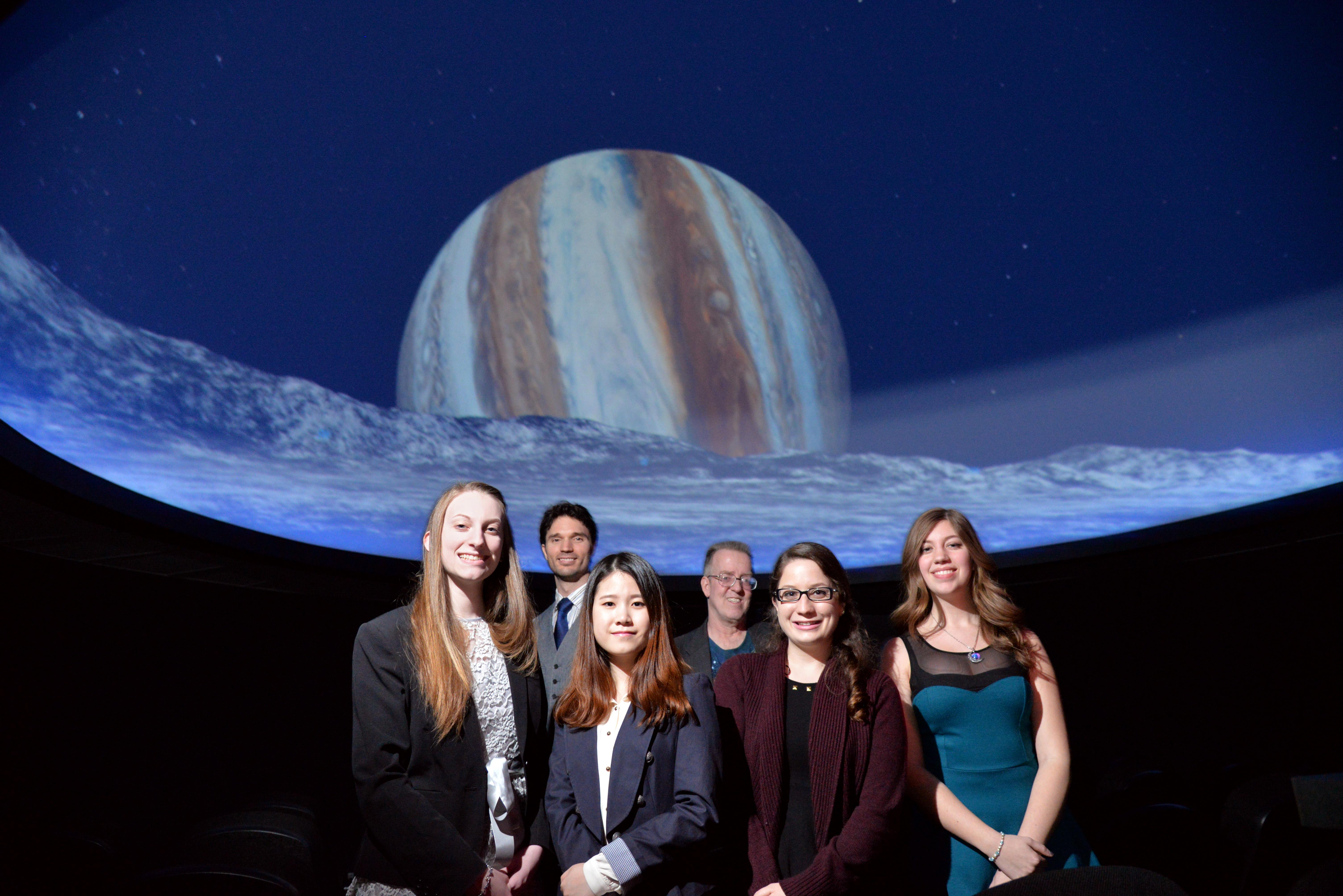 Group of students posing in the planetarium with Professor Roby