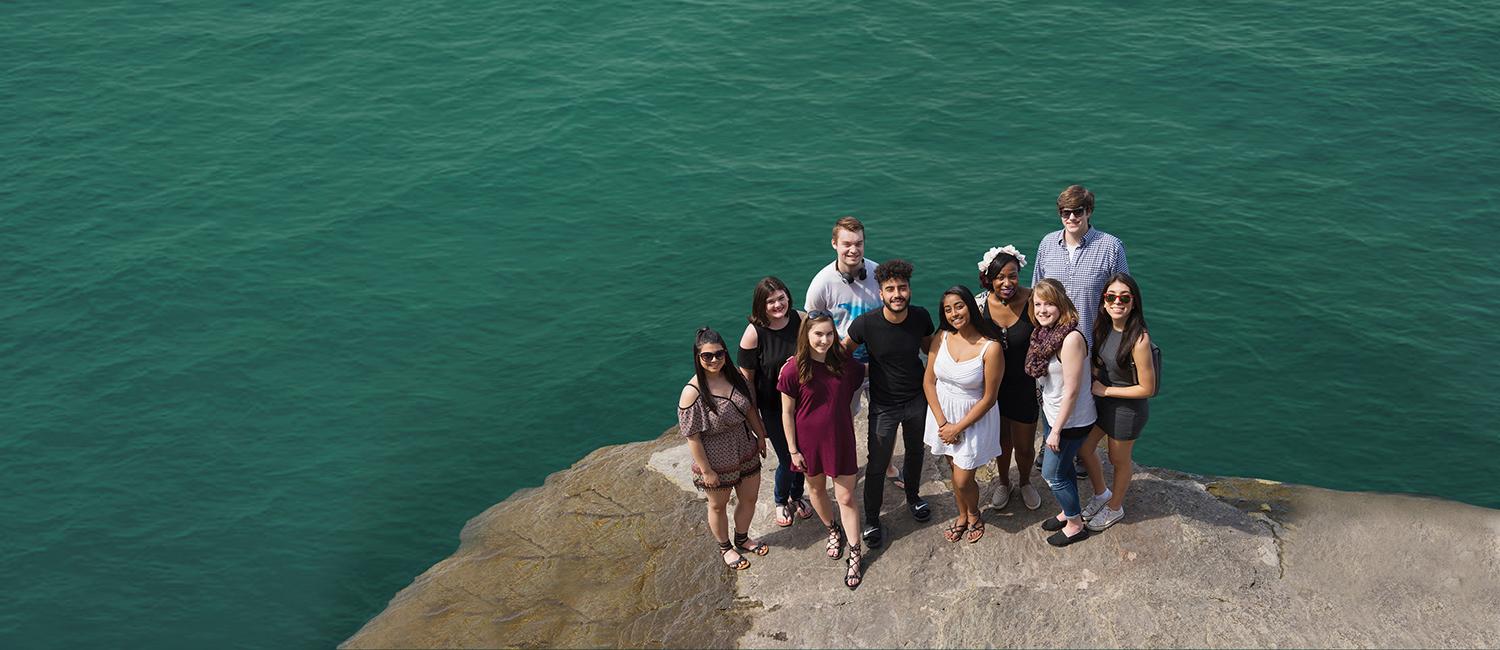 Students stand in a group next to Lake Ontario