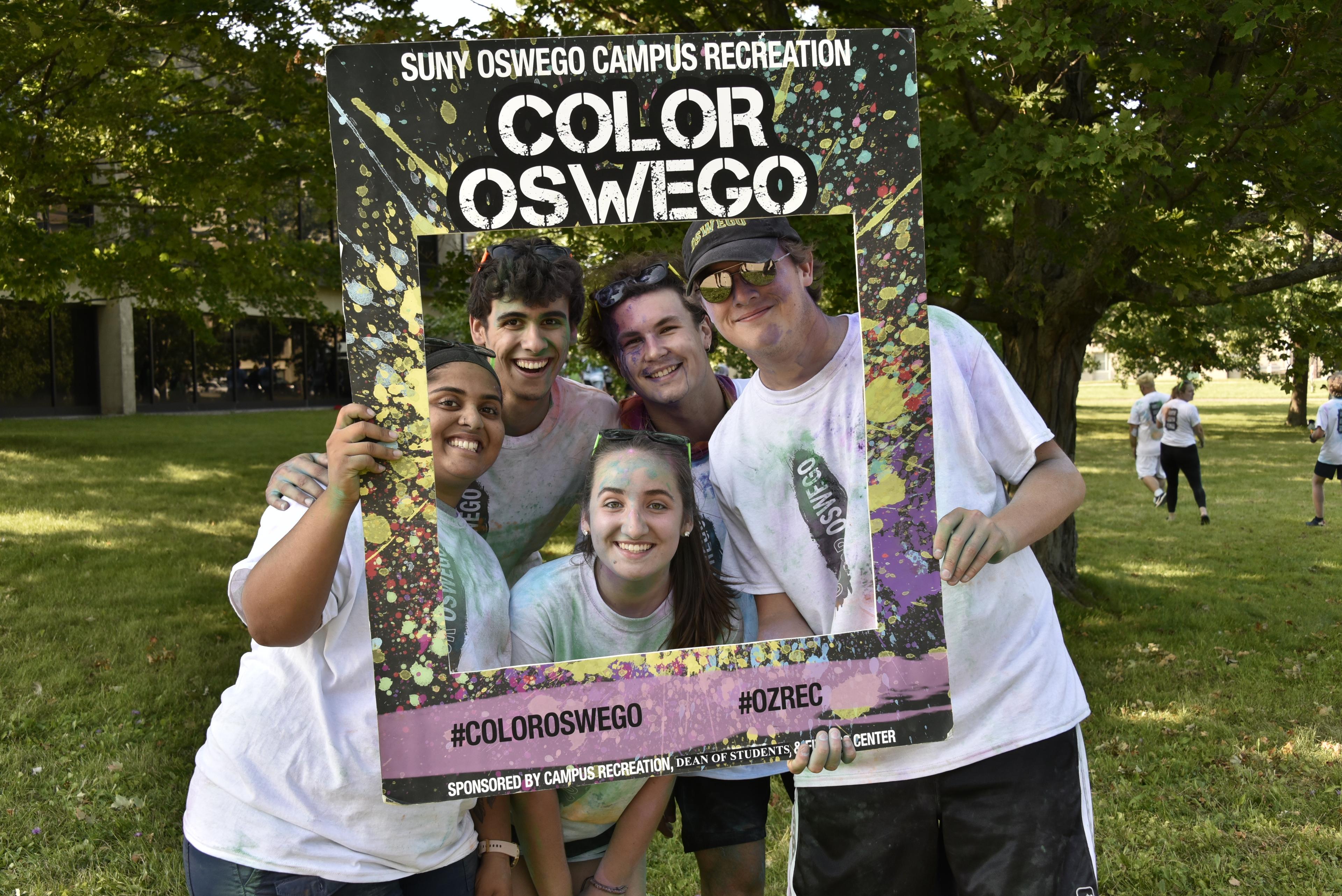 Students posing behind a color run photo frame
